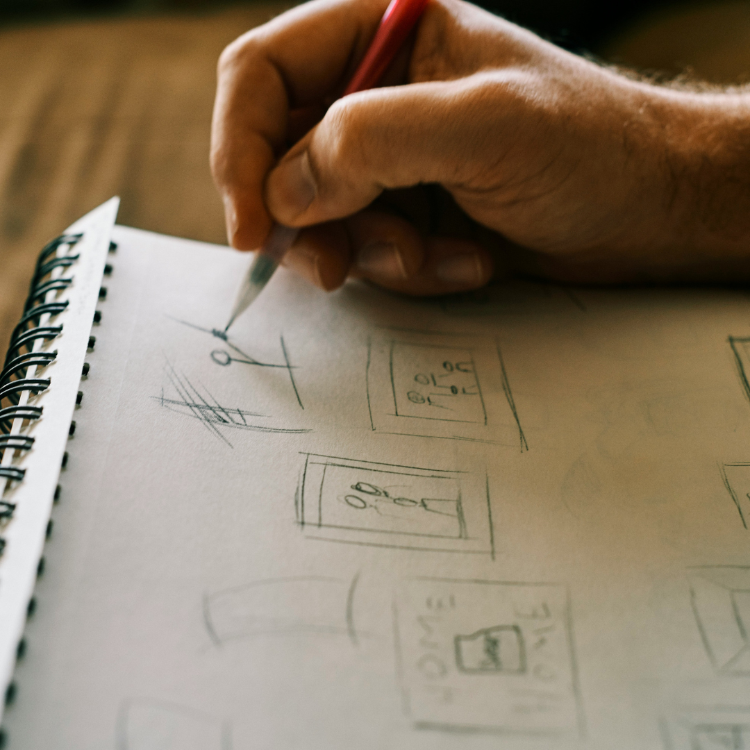 Male hand holding a pencil above a sketchpad