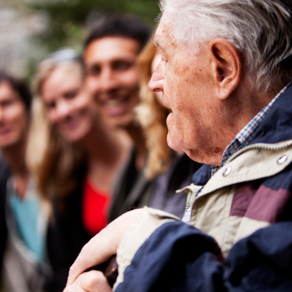 Elderly man speaking to 3 young people to his left