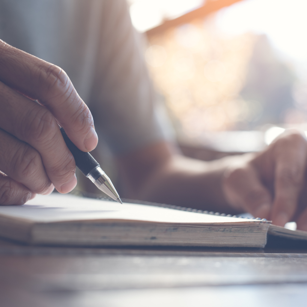 Male hand holding a pen over a notebook
